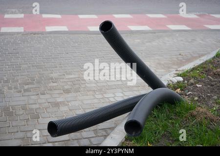 Wellrohre sind in der Nähe der Straße vergraben, Kanalrohre ragen aus dem Boden hervor Stockfoto