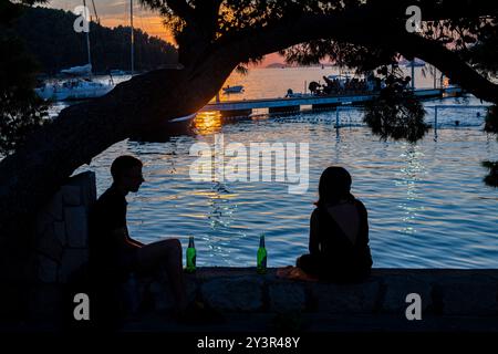 Sitzen Sie unter einem Baum und genießen Sie ein Bier bei Sonnenuntergang in Cavtat, Kroatien Stockfoto