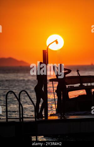 Ein wunderschönes Mädchen duscht, während die Sonne untergeht in Kroatien Stockfoto