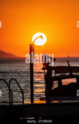 Ein wunderschönes Mädchen duscht, während die Sonne untergeht in Kroatien Stockfoto