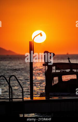 Ein wunderschönes Mädchen duscht, während die Sonne untergeht in Kroatien Stockfoto