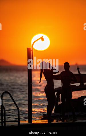 Ein wunderschönes Mädchen duscht, während die Sonne untergeht in Kroatien Stockfoto