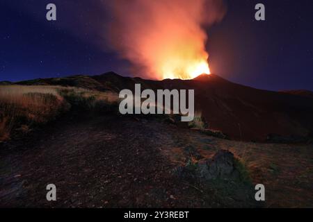 Ätna in eruzione di notte con esplosione di lava dal cratere nel cielo stellato in Sizilien Stockfoto