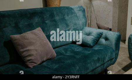 Grünes Kissen oder Kissen auf einem modernen weichen Sofa, ebenfalls in grüner blauer Farbe. Grauer oder hellbrauner Hintergrund. Gemütliches Wohnzimmer oder für einen Psychiater Stockfoto