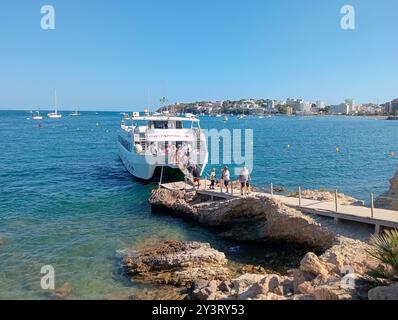 Palmanova, Spanien; 10. august 2024: Ausflugsboot mit Touristen an der felsigen Küste des mallorquinischen Kurortes Palmanova, auf einer sonnigen Insel Stockfoto