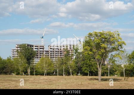 Das Gebäude befindet sich im Bau und blickt über die Bäume eines Parks am blauen Himmel in Bukarest Stockfoto