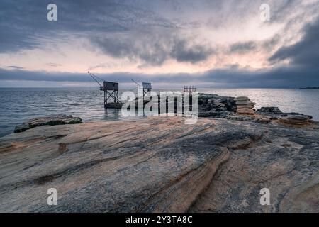Sonnenuntergang entlang der Küste mit traditionellen Carrelets in Charente-Maritime in Frankreich Stockfoto
