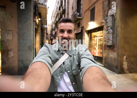 POV junger gutaussehender Mann lächelt beim glücklichen Selfie auf der touristischen Straße der Stadt Barcelona im Hintergrund. Stockfoto