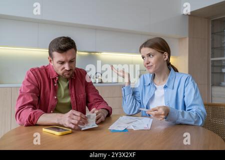 Frustrierte Ehefrau weist den Ehemann, die Familie durchläuft steigende Rechnungen, Steuern, Geldkrise. Stockfoto