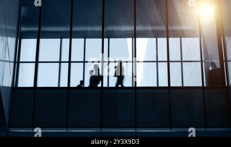 Silhouetten von Geschäftsleuten, die in einem modernen Gebäude laufen Stockfoto