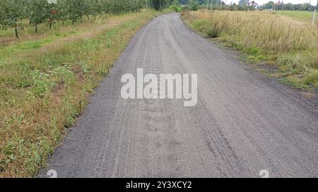 Eine Straße mit einer unbefestigten Straße daneben die Straße ist leer und es gibt keine Autos darauf Stockfoto