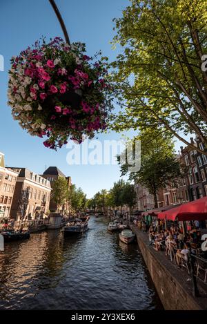 Bezaubernde Kanalszene mit Blumen und Booten in Amsterdam - Niederlande Stockfoto