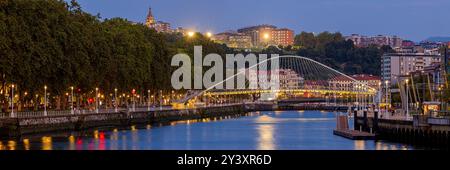 Ein breites 3:1-Panoramablick der spanischen Stadt Bilbao im Baskenland mit Blick auf den Fluss Nervión und die Calatrava-Brücke während der Dämmerung Stockfoto