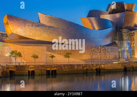 Ein Abend nach Sonnenuntergang in der Dämmerung im berühmten beleuchteten Guggenheim Museum in der spanischen Stadt Bilbao mit seinen markanten Formen und Silber A Stockfoto