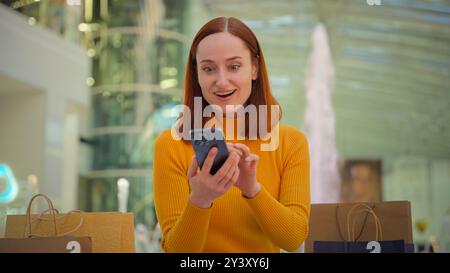 Aufgeregt kaukasische weibliche Kundin Ginger Mädchen Frau lächelnde Geschäftsfrau genießt Browsen Telefon Gadget Internet Shop Online Shopping Verkauf mit Stockfoto