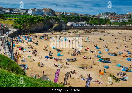 Eine lebhafte Strandszene mit zahlreichen Menschen, die die Sonne genießen. Bunte Sonnenschirme und Strandtücher sind am Sandstrand, während einige Leute schwimmen Stockfoto