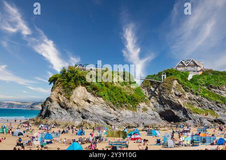 Eine lebhafte Strandszene mit zahlreichen Menschen, die die Sonne genießen, farbenfrohen Strandzelten und felsigen Klippen im Hintergrund. Der Himmel ist hell vor Weisen Stockfoto