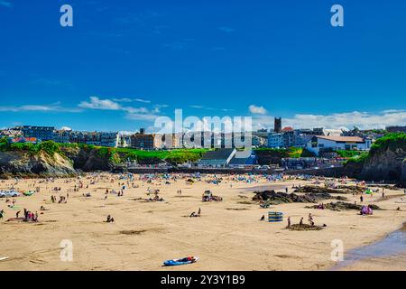 Eine lebhafte Strandszene mit zahlreichen Menschen, die Sonne und Sand genießen. Der Strand ist weitläufig, mit farbenfrohen Sonnenschirmen und Handtüchern, die über den Strand verteilt sind Stockfoto
