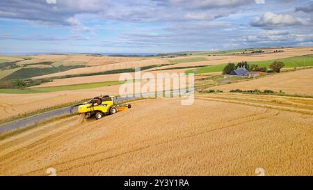 Mähdrescher Gardenstown Aberdeenshire Scotland Harvester im Gerstenfeld Moray Firth in der Ferne Stockfoto