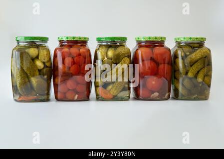 Mehrere Gläser mit Gurken in Dosen, Gurken und Tomaten Stockfoto