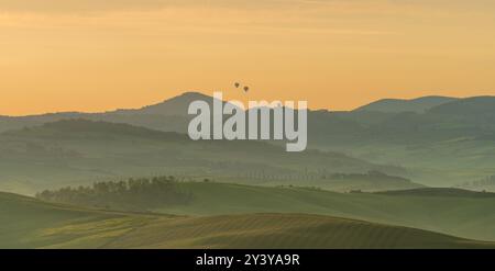 Pienza, Toskana, Italien - 15. September 2024: Haus umgeben von Zypressen zwischen den nebeligen, sonnendurchfluteten Hügeln des Val d'Orcia Tals at Stockfoto