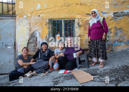 Ankara, Türkei - 13. Juni 2022: Eine generationsübergreifende Gruppe von Frauen und einem Kind versammelt sich vor einem verwitterten gelben Gebäude und teilt einen Moment der Gemeinschaft. Stockfoto