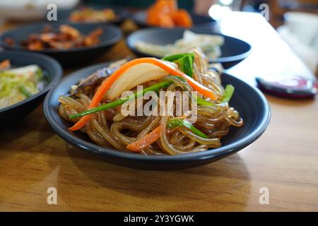 Koreanisches Gericht, das durch Mischen von Nudeln mit dünnen Scheiben von gebratenem Gemüse und Fleisch zubereitet wird Stockfoto