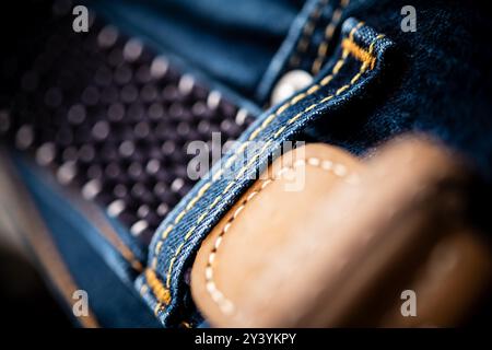 Eine Nahaufnahme des Denim-Materials mit aufwändigen Nähten und einem Lederaufnäher, die die Textur und Qualität moderner Mode betonen. Stockfoto