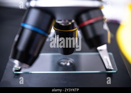 Eine Mikroskoplinse mit hoher Vergrößerung, die über einem vorbereiteten Glasträger positioniert ist und die komplizierten Details für Laboranalysen und wissenschaftliche s zeigt Stockfoto
