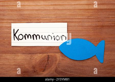 Kommunion. Deutsches Wort. Blauer Fisch in der Ecke. Verlegung auf Holz. Freier Platz für Text. Freier Platz für Text. Stockfoto