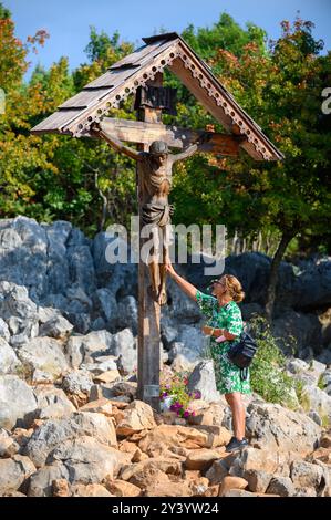 Ein hölzerner gekreuzigter Jesus auf dem Berg Podbrdo, dem Anblick auf das Dorf Medjugorje in Bosnien und Herzegowina. Stockfoto