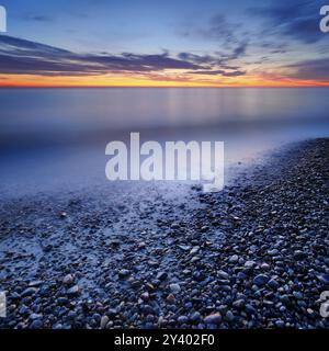 Kieselsteine im Wasser am Ufer der Ostsee in der Abenddämmerung nach Sonnenuntergang, Weststrand Darss, Halbinsel Fischland-Darss-Zingst, Nationalpark Vorpommers Stockfoto