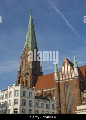 Ein hoher gemauerter Kirchturm erhebt sich in den blauen Himmel, umgeben von Gemeindegebäuden, schwerin, mecklenburg Stockfoto