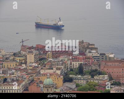 Blick auf eine Küstenstadt mit einem Hafen und einem großen Schiff im Hintergrund, neapel, mittelmeer, italien Stockfoto