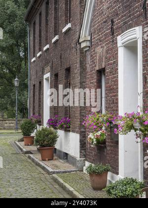 Backsteinbau mit Blumentöpfen vor den Fenstern, Lampen und Kopfsteinpflaster in einer ruhigen Straße, Huenxe, Niederrhein, Deutschland, Europa Stockfoto