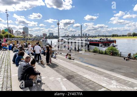 Düsseldorf, Deutschland - 25. August 2024: Stadtansicht von Düsseldorf am Rhein im Sommer. Leute sitzen auf den Stufen zum Rheinufer Stockfoto