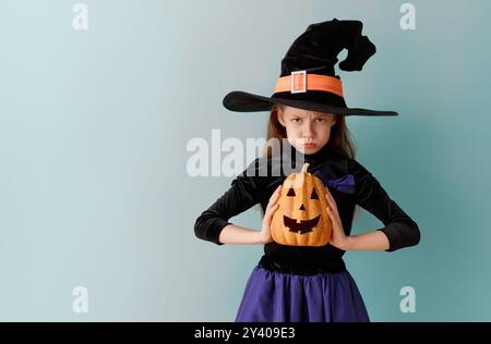 Die wütende kleine Hexe. Mädchen im Halloween-Kostüm auf blauem Hintergrund. Stockfoto