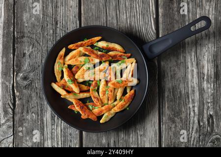 Schupfnudeln, Fingernudeln, deutsche Kartoffeldicknudeln, Knödel in einer Pfanne auf rustikalem grauen Holztisch, horizontale Ansicht von oben, flache Lage, Stockfoto