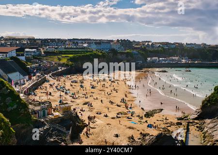 Eine lebhafte Strandszene mit zahlreichen Menschen, die das sonnige Wetter genießen. Am Sandstrand gibt es bunte Sonnenschirme und Strandtücher, während Wellen liegen Stockfoto