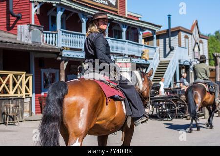 Weiblicher Cowboy, der in der Stadt reitet Stockfoto