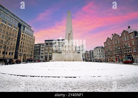 Verschneite Damplatz in Amsterdam Niederlande mit dem Nationaldenkmal im Winter bei Sonnenuntergang Stockfoto