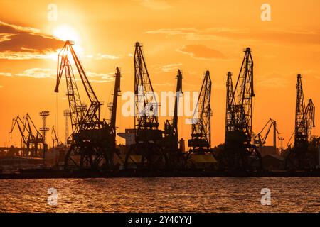 Silhouetten für Seehäfen und Industriekrane, Varna, Bulgarien. Sonnenuntergang über dem Varna-See. Silhouetten von Seehäfen und Industriekranichen Stockfoto