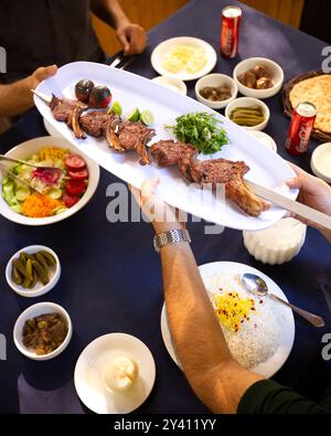 Ein genauerer Blick auf gegrillte Lammkoteletts, garniert mit frischen Kräutern und verkohltem Gemüse Stockfoto