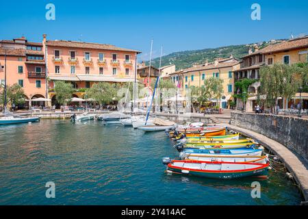 Wunderschöne Aussicht auf farbenfrohe Boote im Hafen von Torri del Benaco am Ufer des Gardasees, Italien Stockfoto