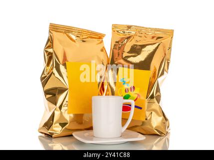 Zwei Vakuumverpackungen Kaffeebohnen mit weißer Keramikschale und Untertasse, Makro, isoliert auf weißem Hintergrund. Stockfoto