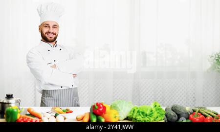 Koch-Typ In Uniform Posiert Crossing Hands In Restaurant Kitchen Stockfoto