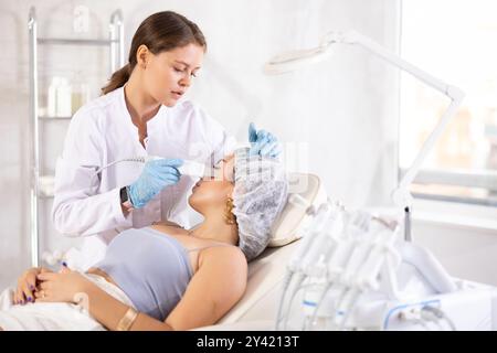 Ästhetiker bei der Durchführung von Gesichtsbehandlungen an jungen Frauen mit Ultraschallschaufeln Stockfoto