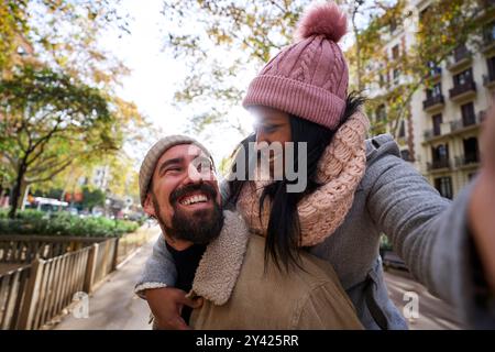 Glückliches Liebespaar, das draußen in der Stadt ein Selfie macht und sich fröhlich ansieht. Stockfoto