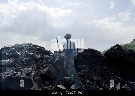 Dhanbad, Jharkhand, Indien. 31. August 2024. Ein Arbeiter arbeitet auf einem Kohlehaufen in der Nähe eines Tagebaues am Stadtrand von Dhanbad. In Jharia im indischen Bundesstaat Jharkhand leben rund 600.000 Menschen. Es liegt im Herzen des größten Kohlefeldes der Nation. Jharia, das seinen Namen von der Stadt und Region mit dem gleichen Namen erhält, ist auch bekannt für eine schreckliche Rate von Kohleflözbränden, die eine der Hauptquellen der Umweltverschmutzung in der Region und weltweit sind. Kohlendioxid wird durch Kohlebrände in massiver Menge in die Atmosphäre abgegeben. (Kreditbild: © Stockfoto