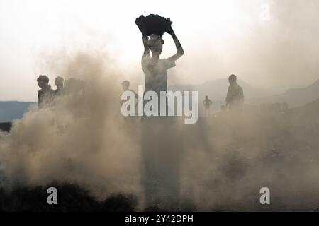 Dhanbad, Jharkhand, Indien. 31. August 2024. Die Arbeiter transportieren Kohle in der Nähe eines Tagebaues am Stadtrand von Dhanbad. In Jharia im indischen Bundesstaat Jharkhand leben rund 600.000 Menschen. Es liegt im Herzen des größten Kohlefeldes der Nation. Jharia, das seinen Namen von der Stadt und Region mit dem gleichen Namen erhält, ist auch bekannt für eine schreckliche Rate von Kohleflözbränden, die eine der Hauptquellen der Umweltverschmutzung in der Region und weltweit sind. Kohlendioxid wird durch Kohlebrände in massiver Menge in die Atmosphäre abgegeben. (Bild: © Amarjeet Kumar S Stockfoto